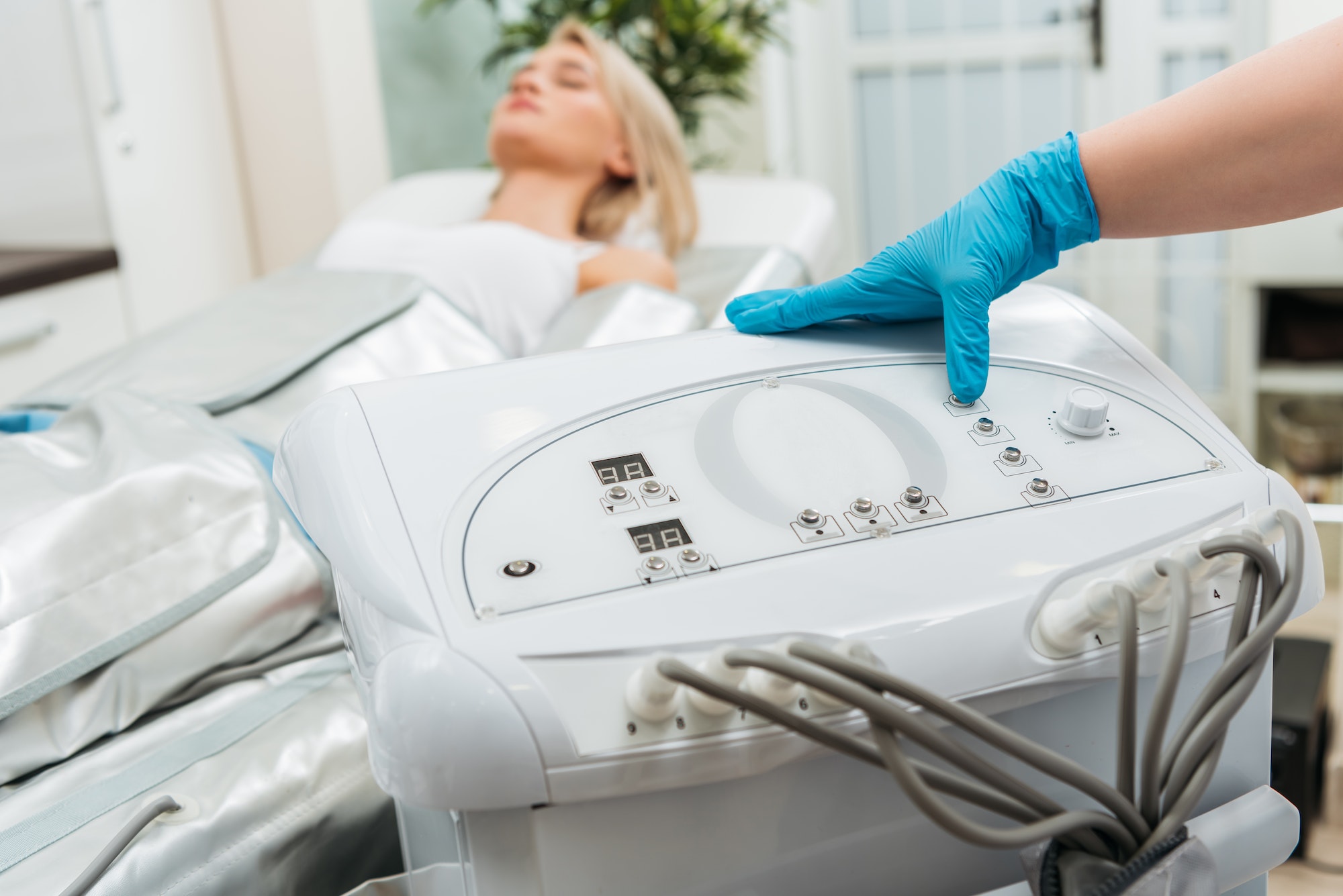 Cropped view of cosmetologist setting up machine for pressotherapy