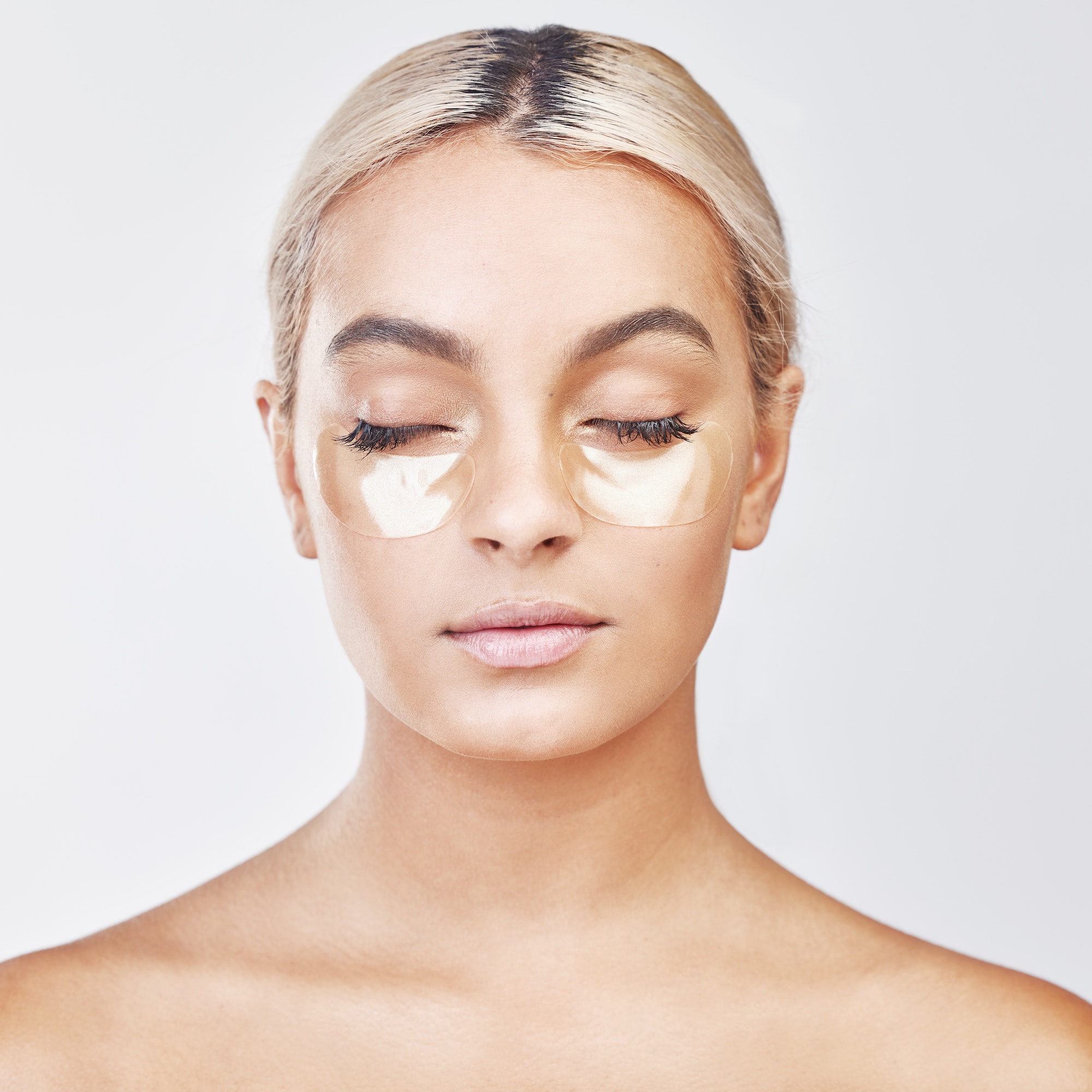 Studio shot of a beautiful young woman wearing an under-eye beauty patch against a grey background
